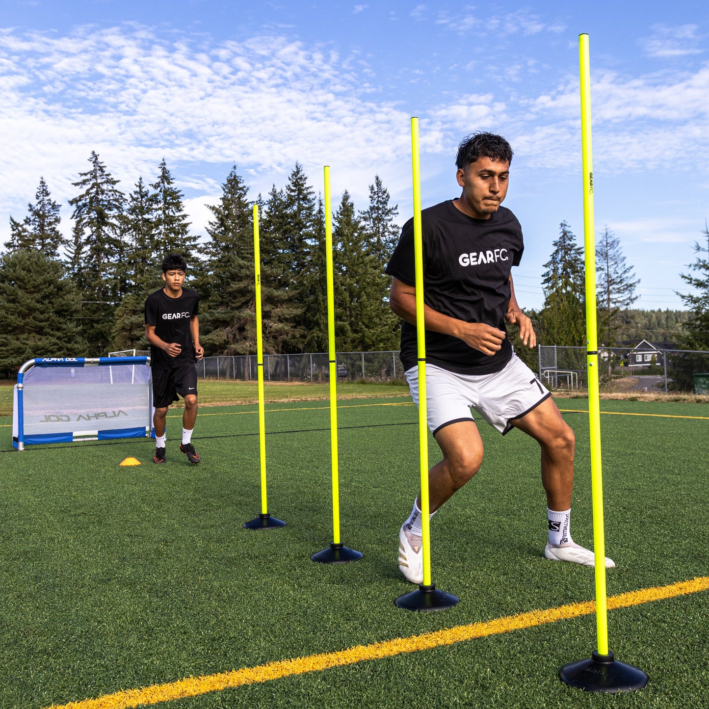 Soccer players training with agility poles on green turf