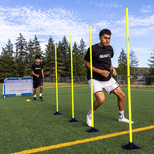 Soccer players training with agility poles on green turf