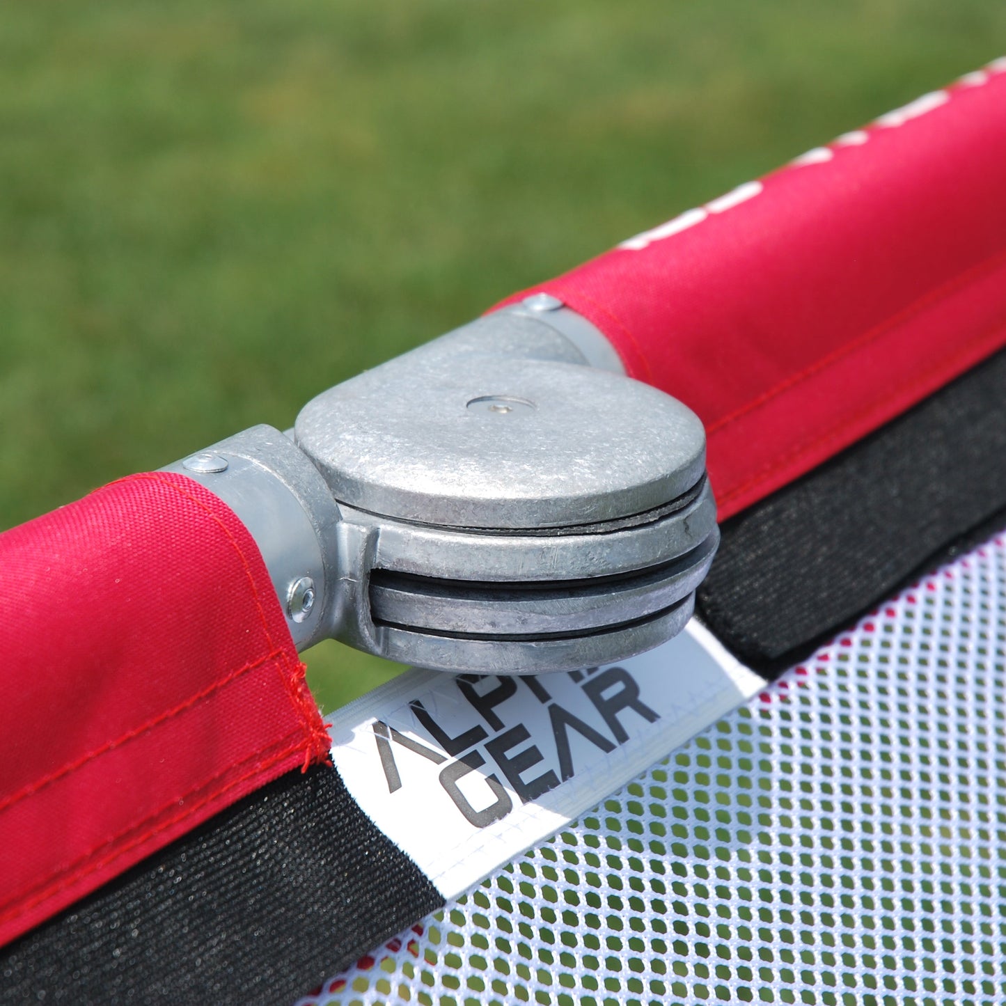 Folding hinge mechanism on red soccer goal frame with padded uprights either side