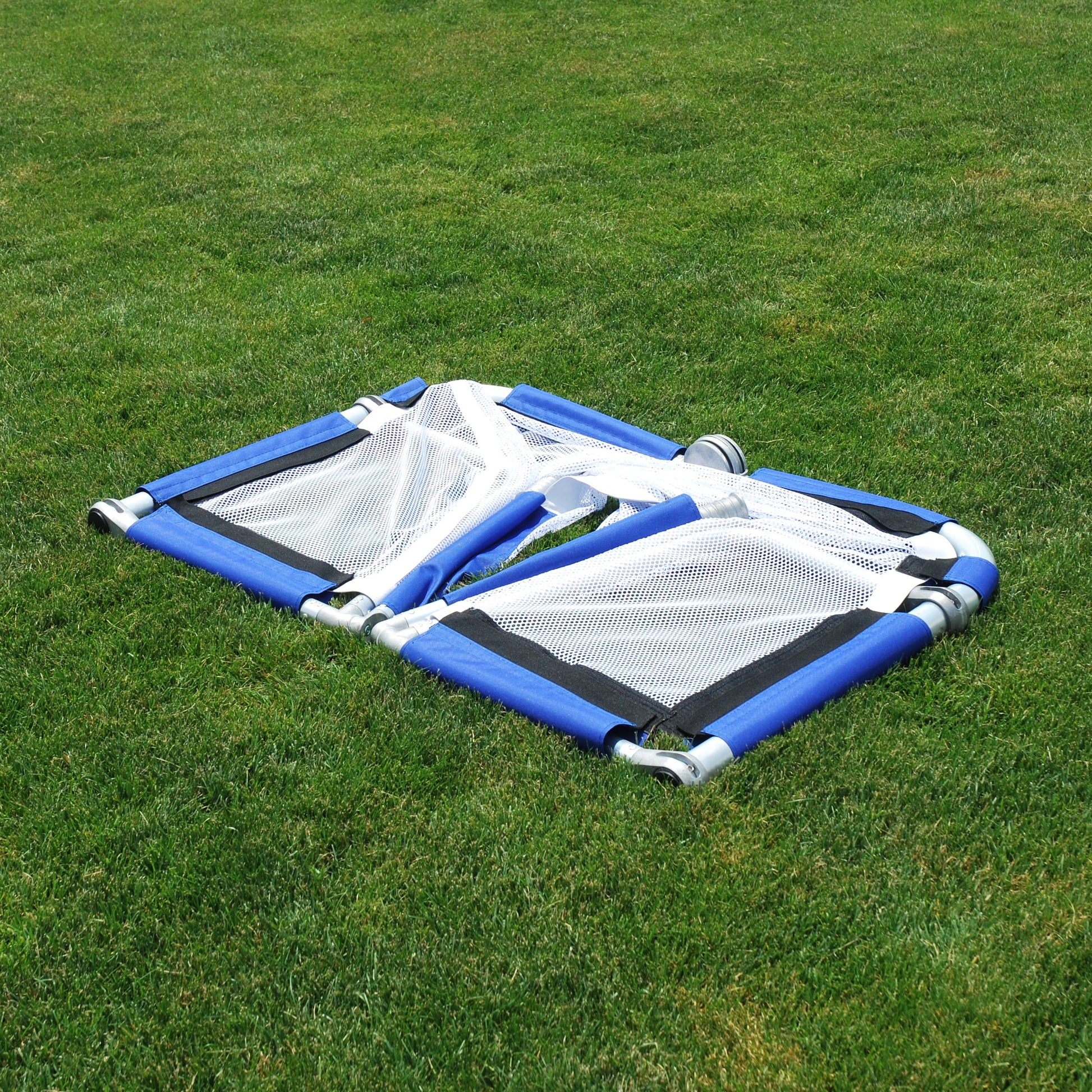 Royal soccer goal half-folded on grass, silver aluminum frame with white mesh netting