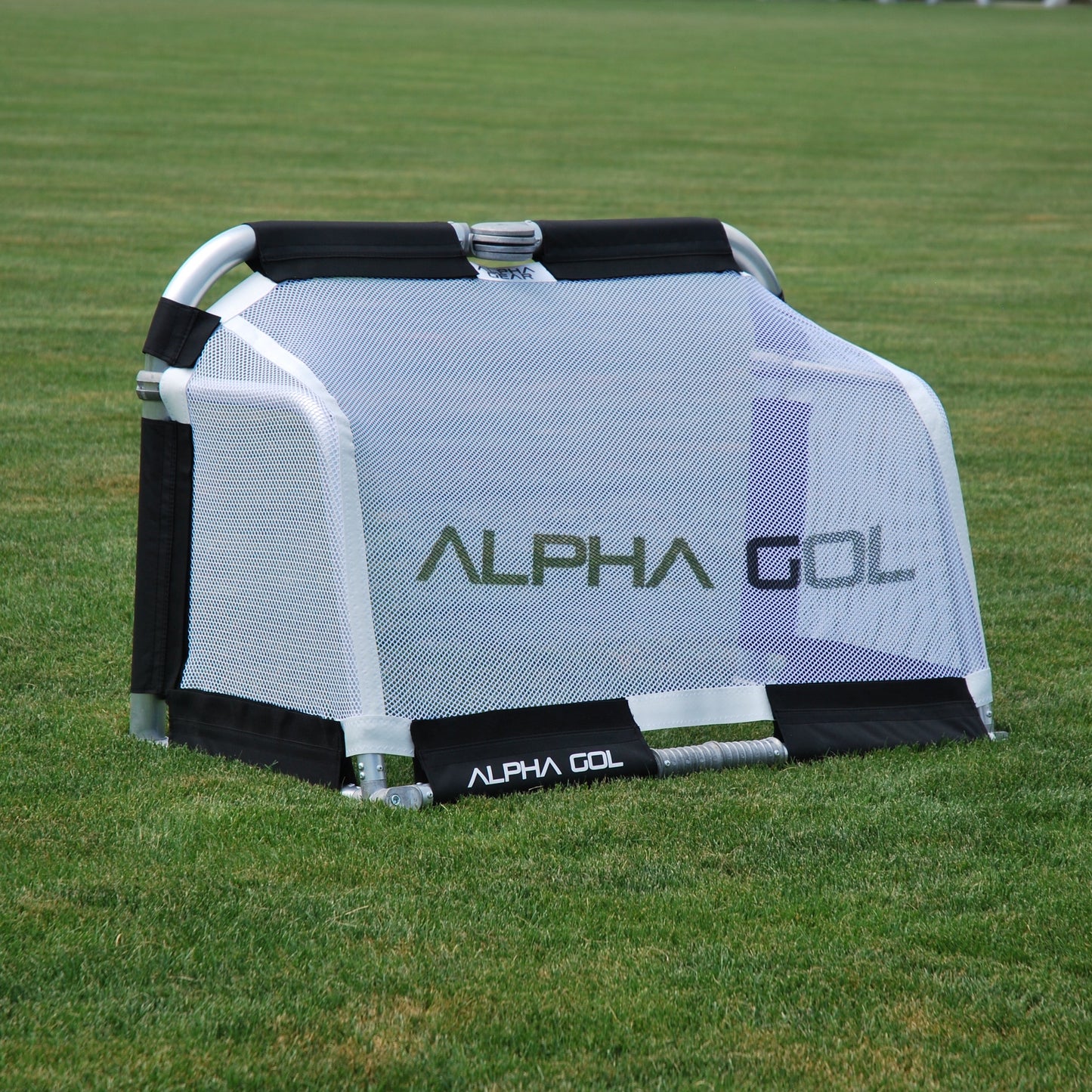 Black folding soccer goal on grass, back view, silver aluminum frame with white mesh netting