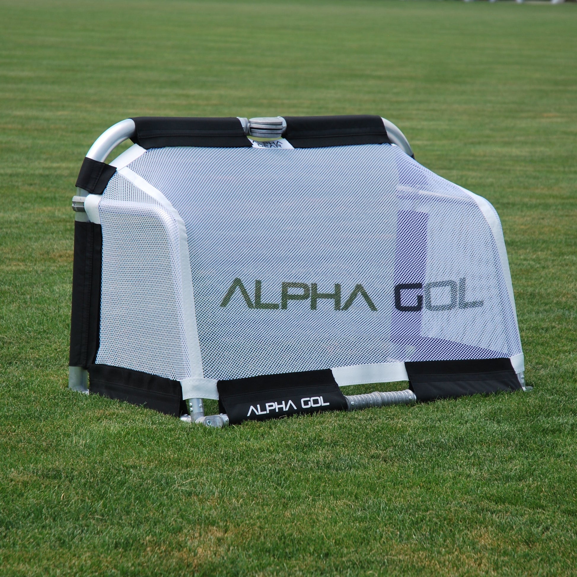 Black folding soccer goal on grass, back view, silver aluminum frame with white mesh netting